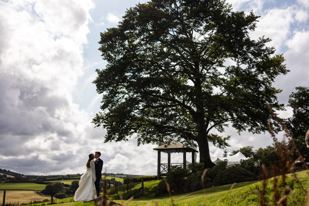 couple embrace the views in front of the big oak tree at little quarme