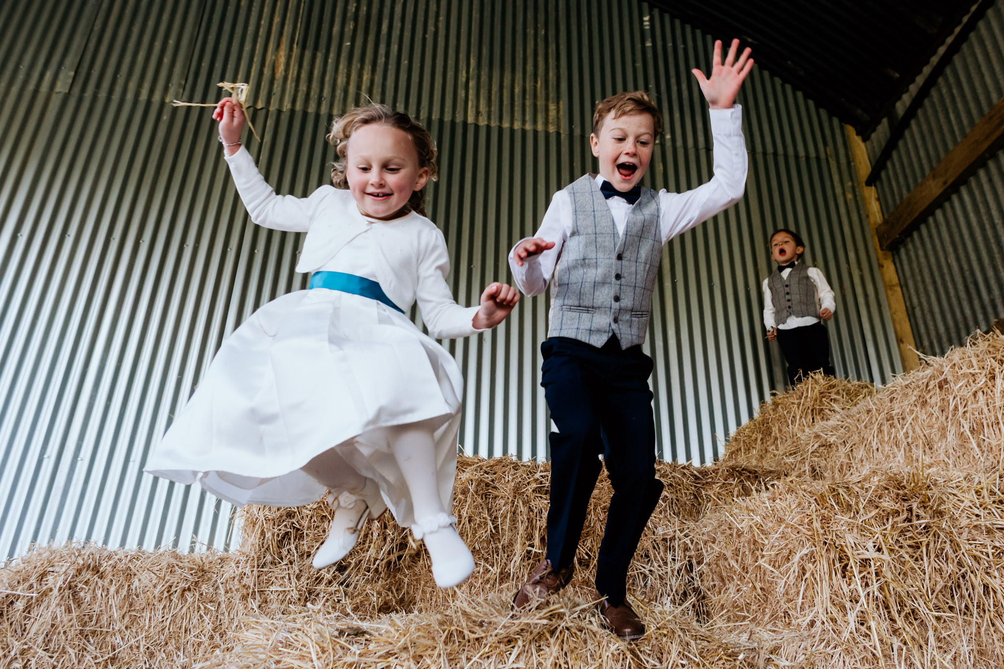 kids jumping off hay bales at anran summer wedding devon