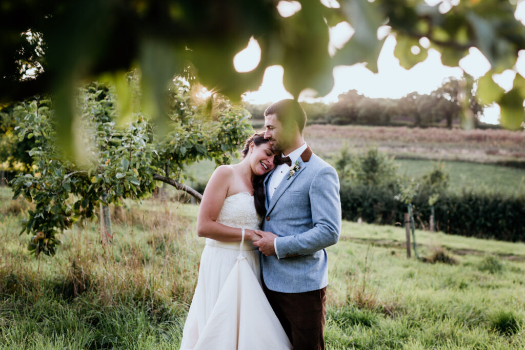 newly wed couple embrace in the fields around bickham barn