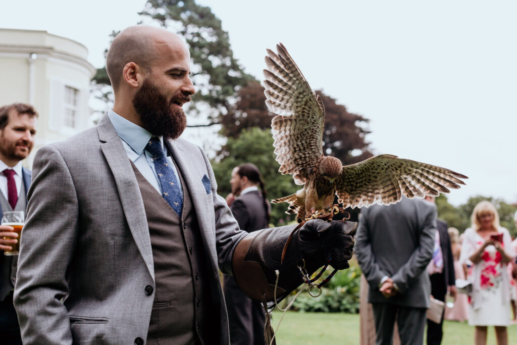 groomsman holds bird of prey at the deer park estate wedding