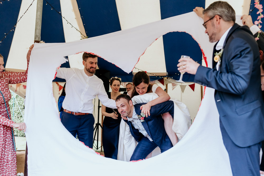 a unique couple getting piggybacked through a cut out heart during their international wedding at colehayes park
