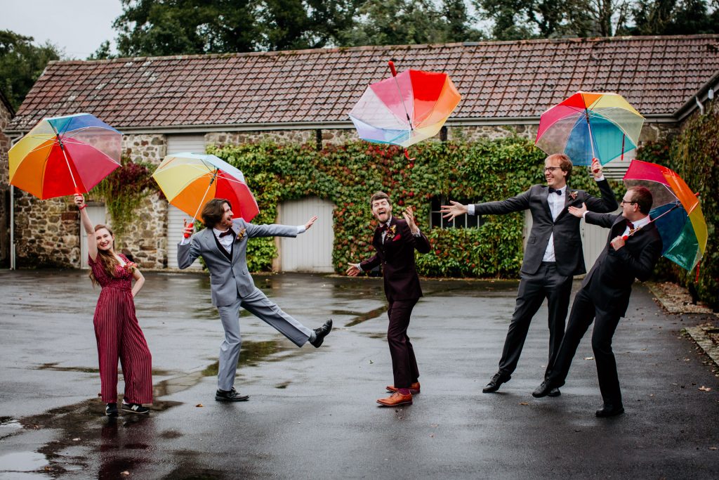 groom and guests at a rainy wedding with umbrellas