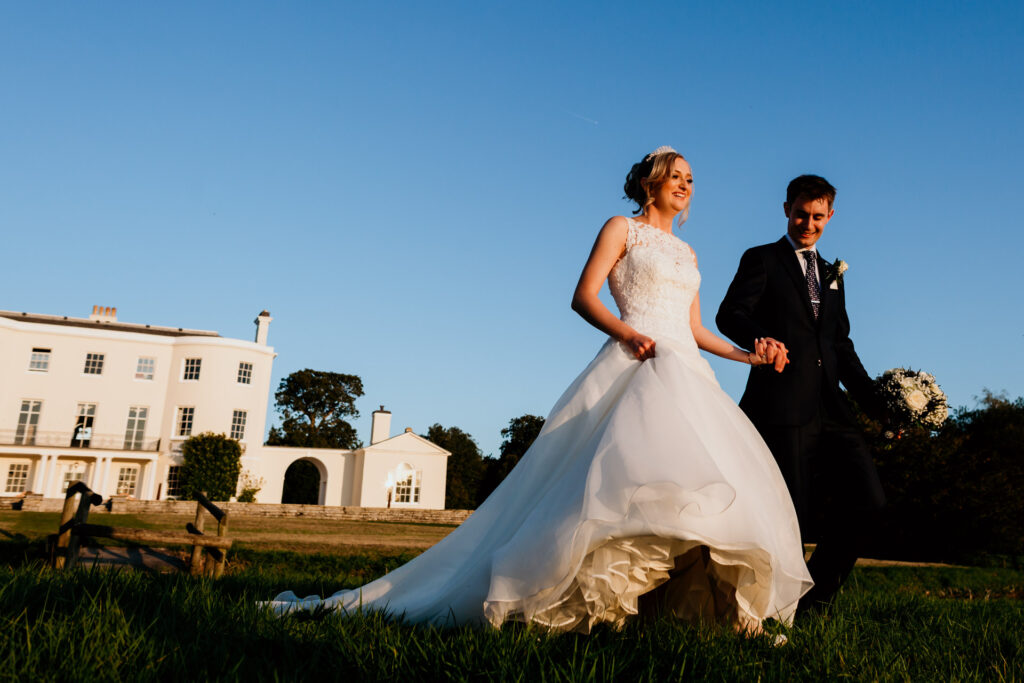 couple walk towards sunset at rockbeare manor wedding