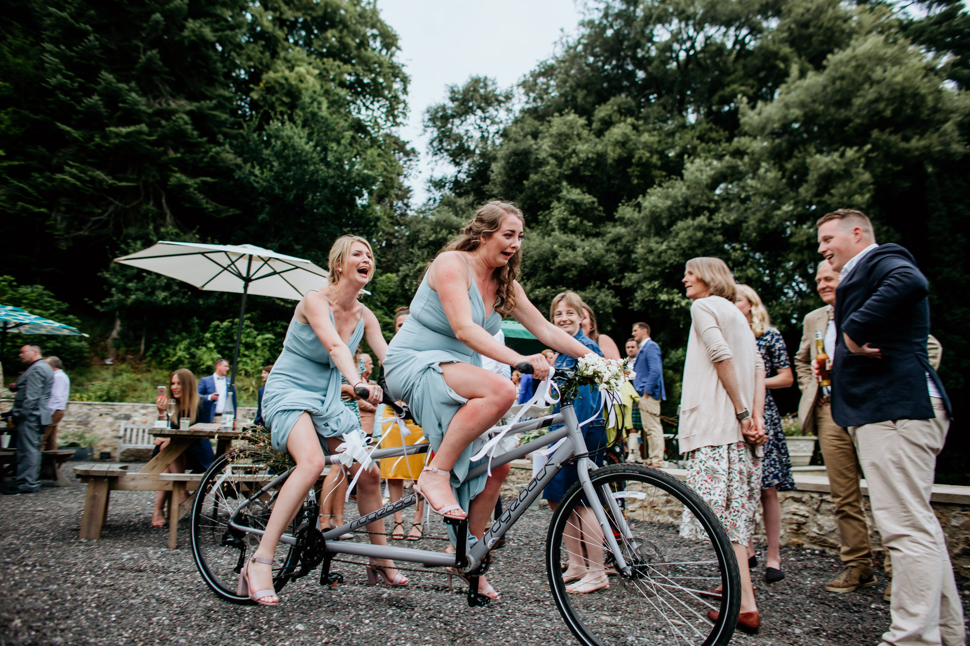 bridesmaids riding on a tandem bike at a wedding and laughing
