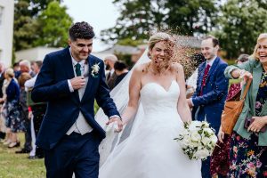 a bride gets pelted with natural petal confetti at a rockbeare manor wedding