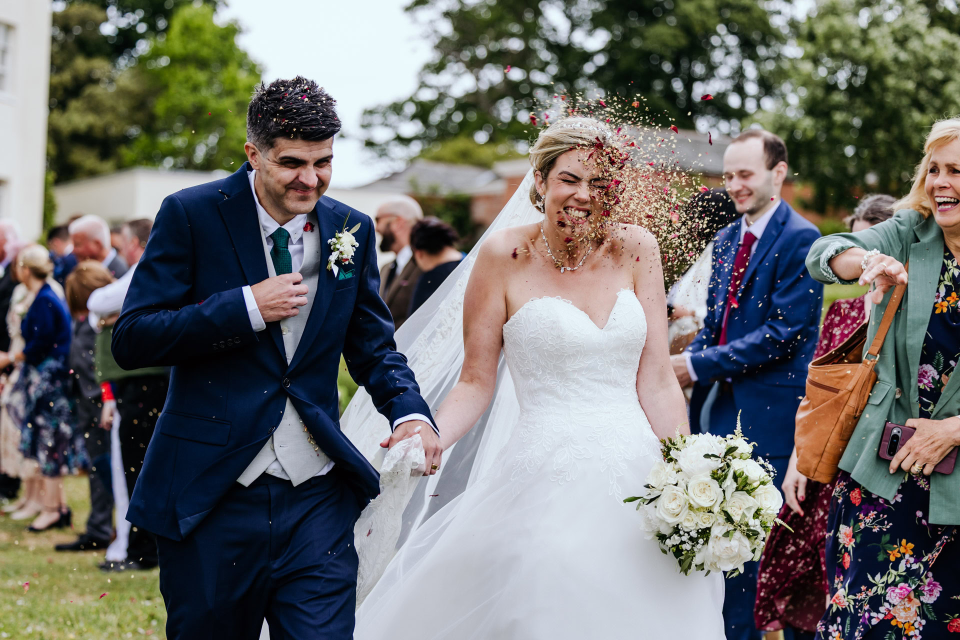 a bride gets pelted with natural petal confetti at a rockbeare manor wedding