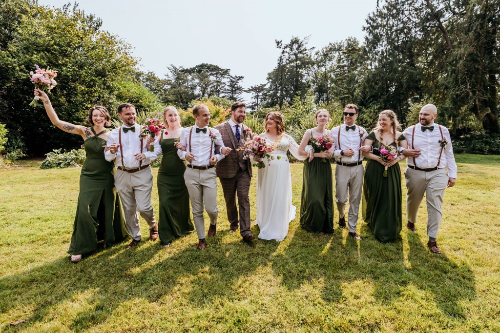 the wedding party link arms at ashridge great barn