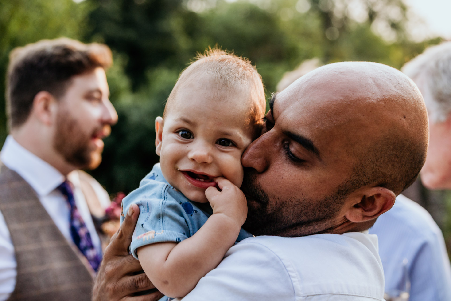 a dad kisses his baby at a wedding