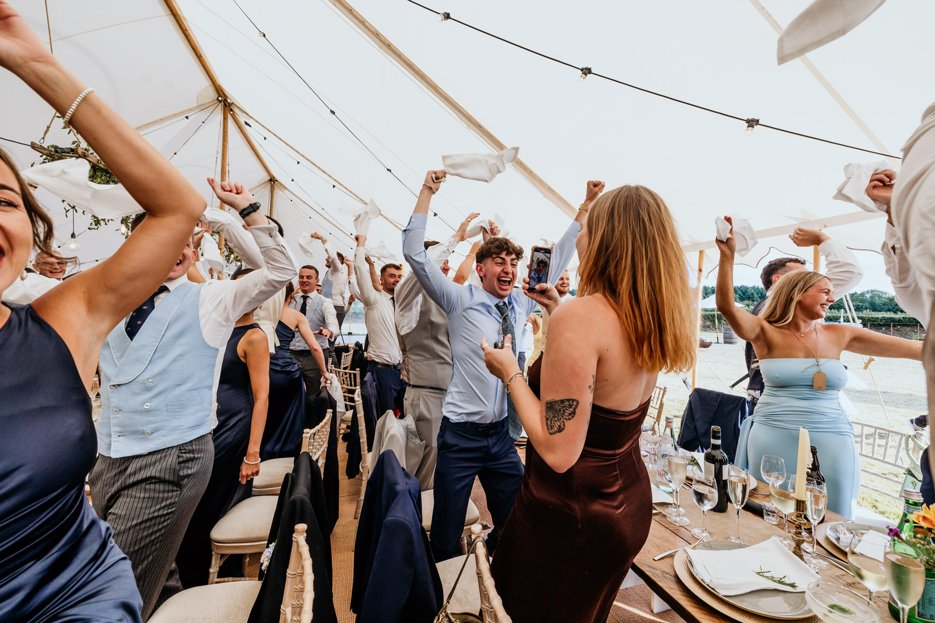 guests wave napkin for a the entrance of the bride and groom in a marquee