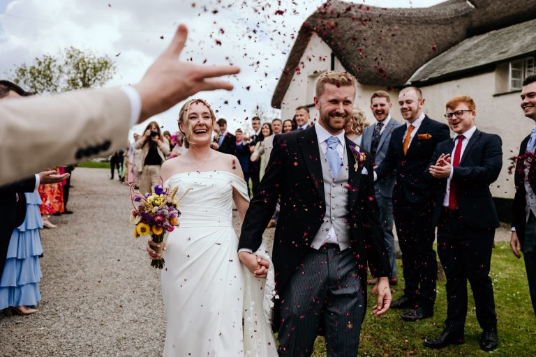 a hand throws confetti at the bride and groom at higher eggbeer