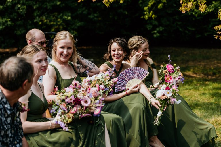 bridemaids fan themselves at the outside ceremony at ashridge great barn cicle garden
