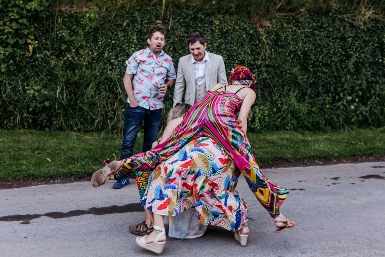 a bride leapfrogs over a guest in her sparkly evening jumpsuit