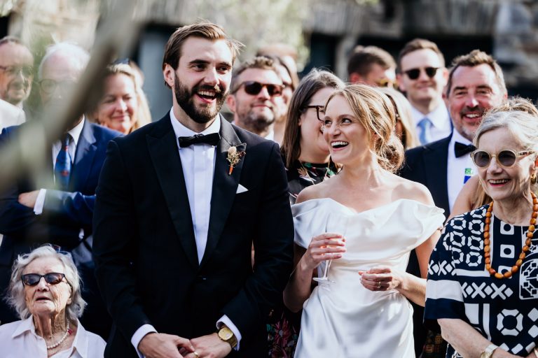 a bride and groom look at each other and laugh at their outdoor courtyard speeches at Anran