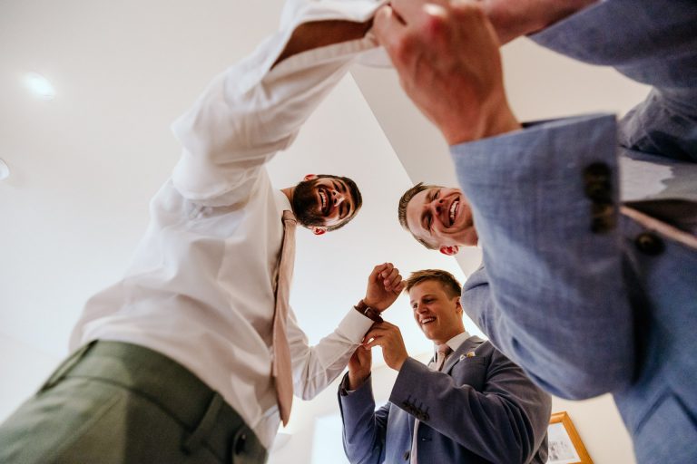 two groomsmen fix the grooms cufflinks - shot from below