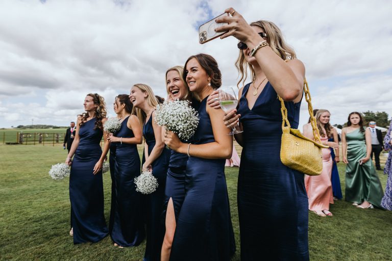 bridemaids look on and photograph the action
