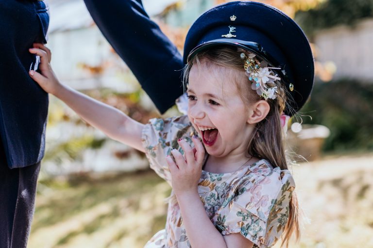 a flower girl wears her dads military hat