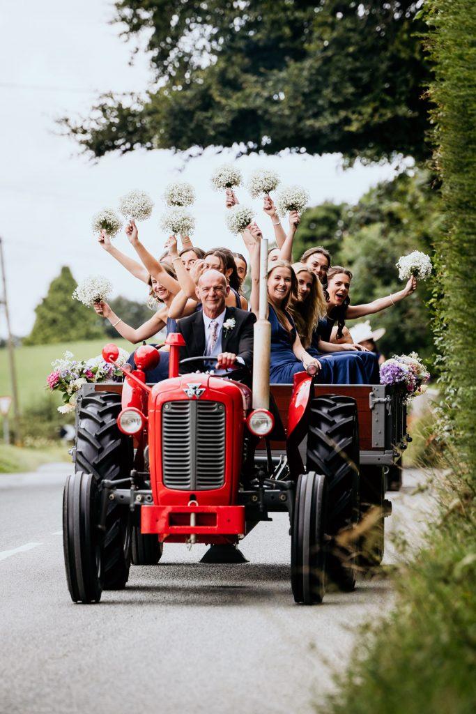 bridemaids arrive at the ceremony on a red tractor