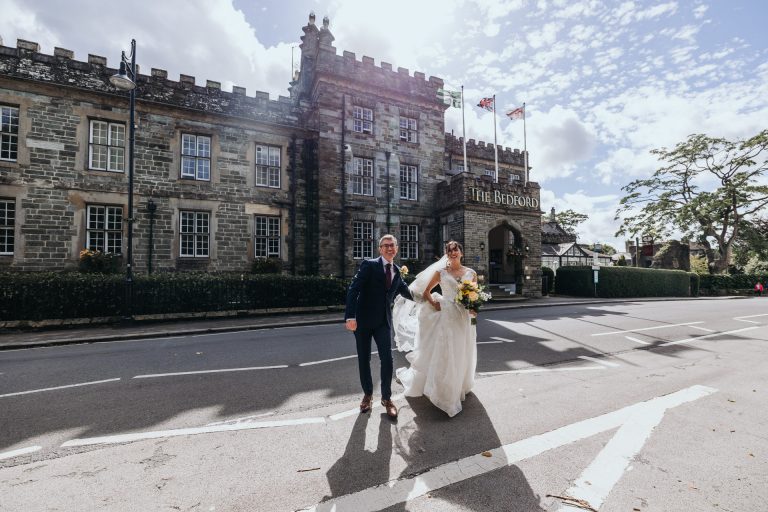 a bride and her father crossing the road to the church from the bedford hotel in tavistock