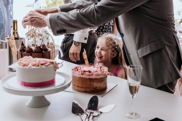 a young flower girl gets excited for wedding cake