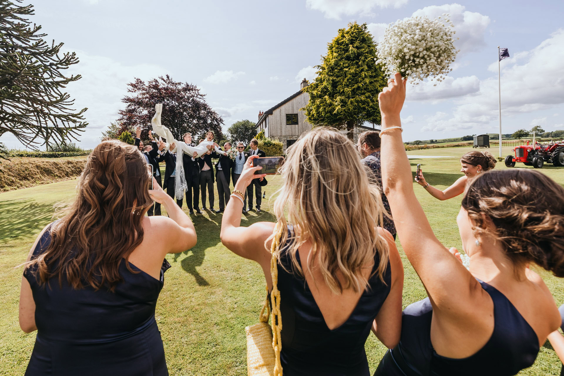bridesmaids cheer on the bride as she is lifted up by the groomsmen at a marquee wedding in devon