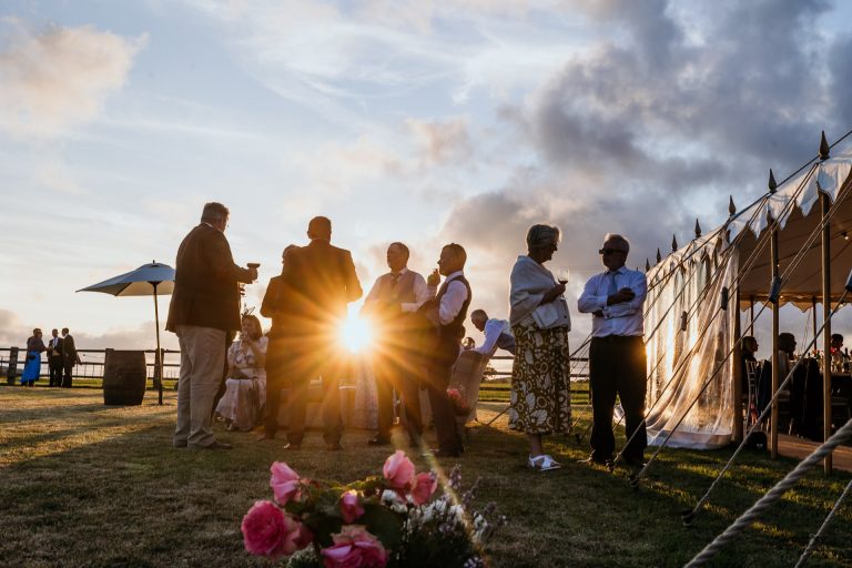 the sun goes down behind the guests outside a devon marquee wedding