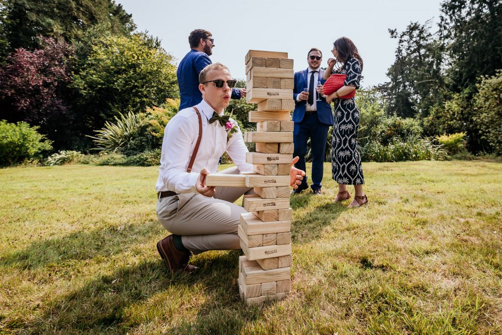 groomsman contemplates his next move at giant Jenga in the gardens at Ashridge Great barn