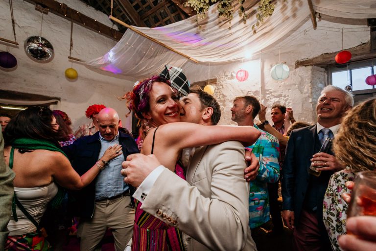 a warm embrace of the bride and groom as they dance with each other and their friends