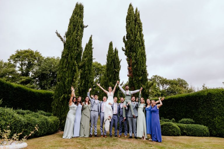 fun wedding party shot with the bride and groom up on shoulders in the gorgeous grounds of the great barn in devon