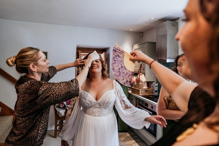bride gets sponged down in the heat of an august wedding