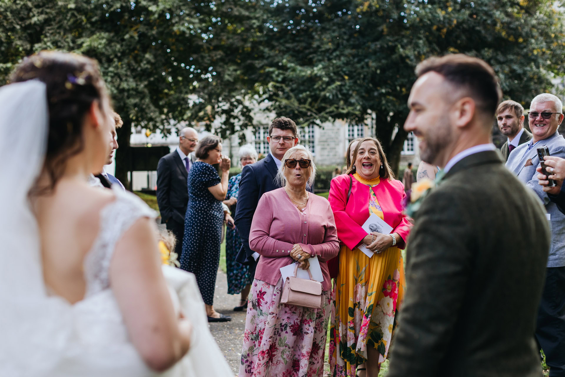 aunties gasp at the bride outside a church wedding in tavistock
