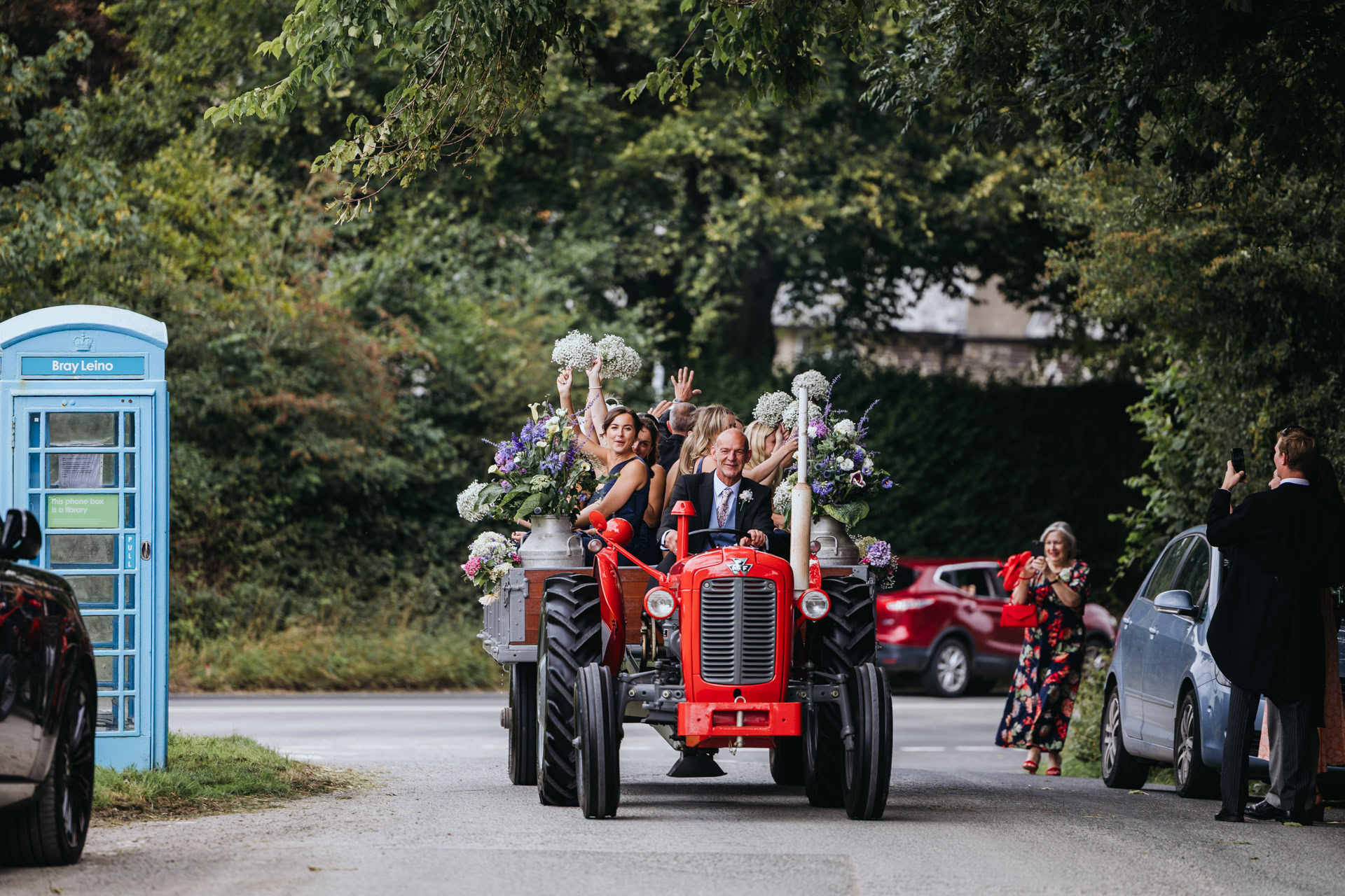bride groom and bridesmaids leave the ceremony on a tractor