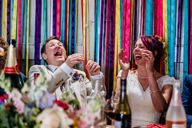 bride and groom laugh hysterically at the speeches