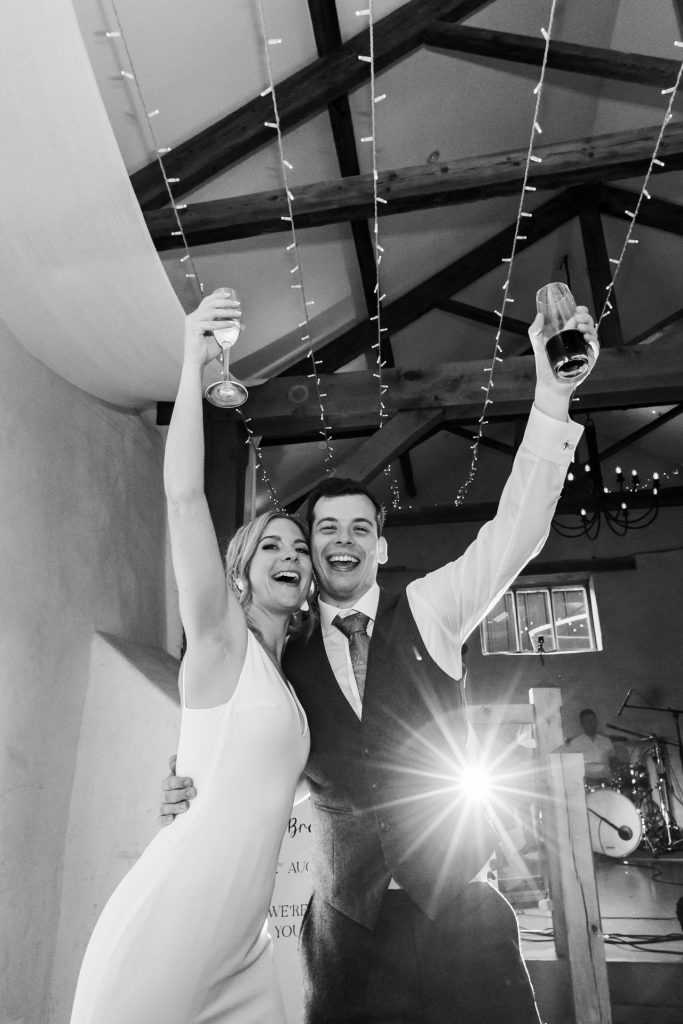 bride and groom celebrate with drinks on the dancefloor at upton barns