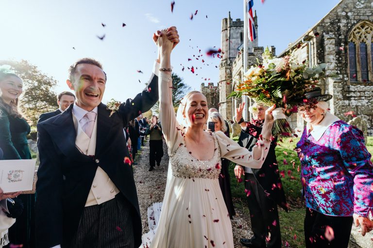 a couple celebrate their marriage surrounded by flying confetti at manaton church devon