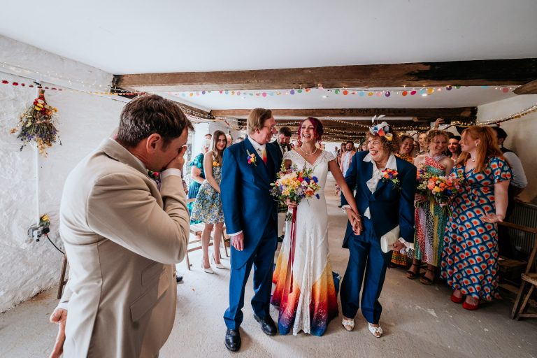 mum and dad walk a bride down the aisle in matching suits as a surprise to her at bradstone manor