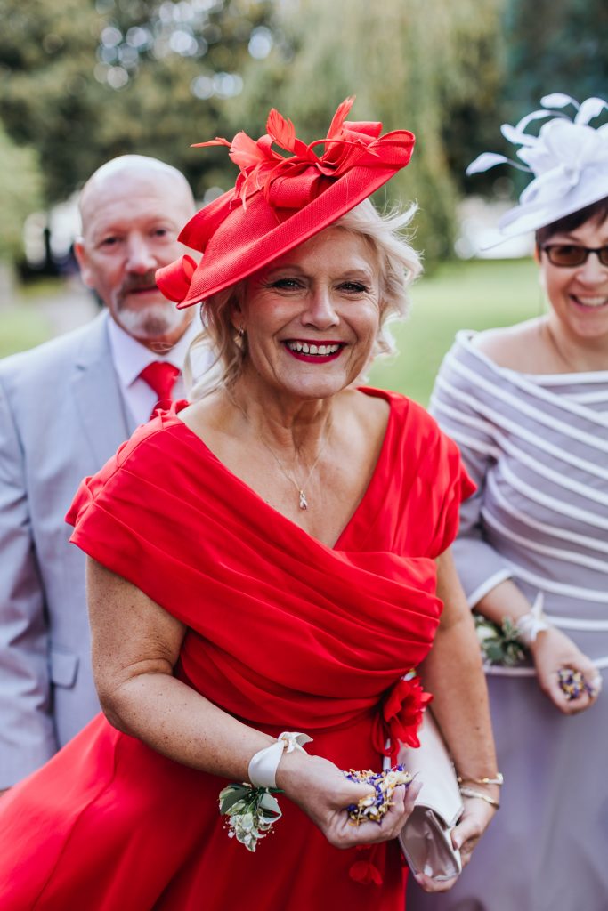 mother of the groom dressed in red gets ready to throw confetti