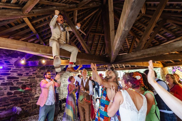 a groom climbs up to the rafters to dance