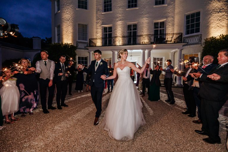 bride and groom and sparlkels outside rockbeare manor