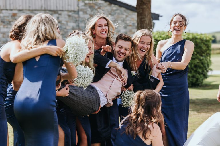 bridesmaids lift up the groom at a farm wedding