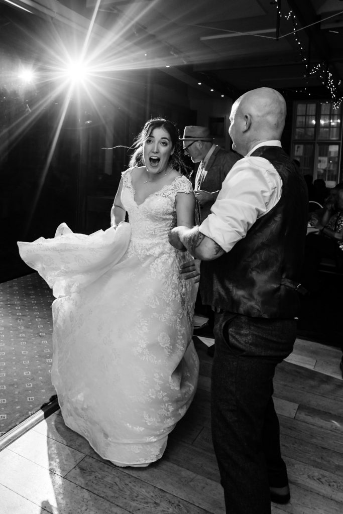 bride dances with a guest in black and white image