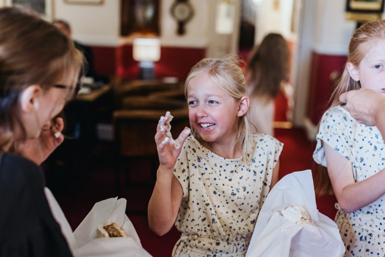 a kid gets a very sticky hand from the wedding cake
