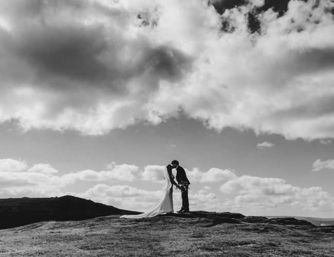 couple embrace at the top of a tor on a small dartmoor devon wedding